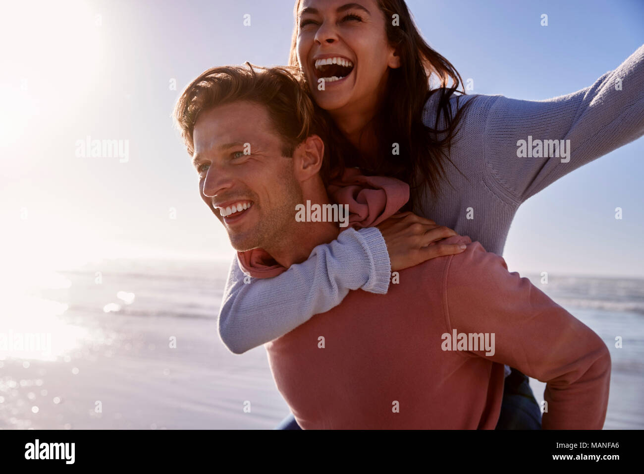 Uomo Donna dando piggyback sulla spiaggia invernale Vacanza Foto Stock