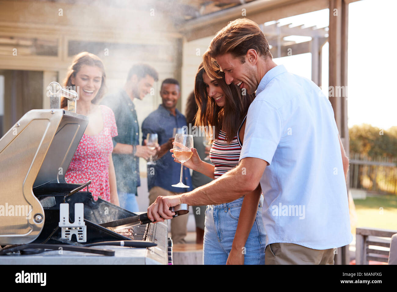 Gruppo di amici gustando un barbecue a casa insieme Foto Stock