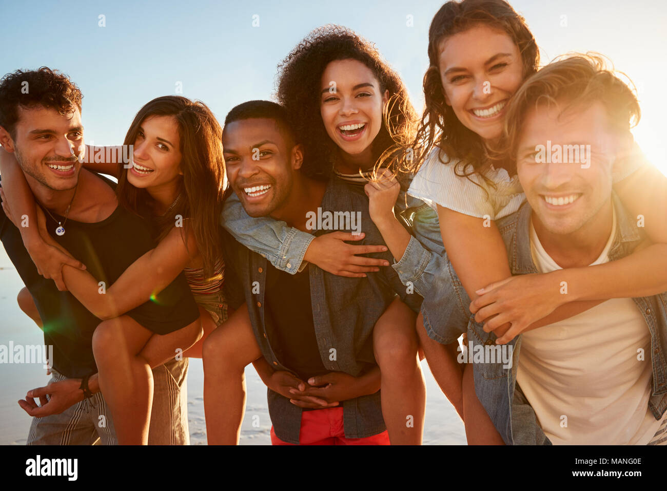 Gruppo di amici in vacanza avente Piggyback gara sulla spiaggia Foto Stock