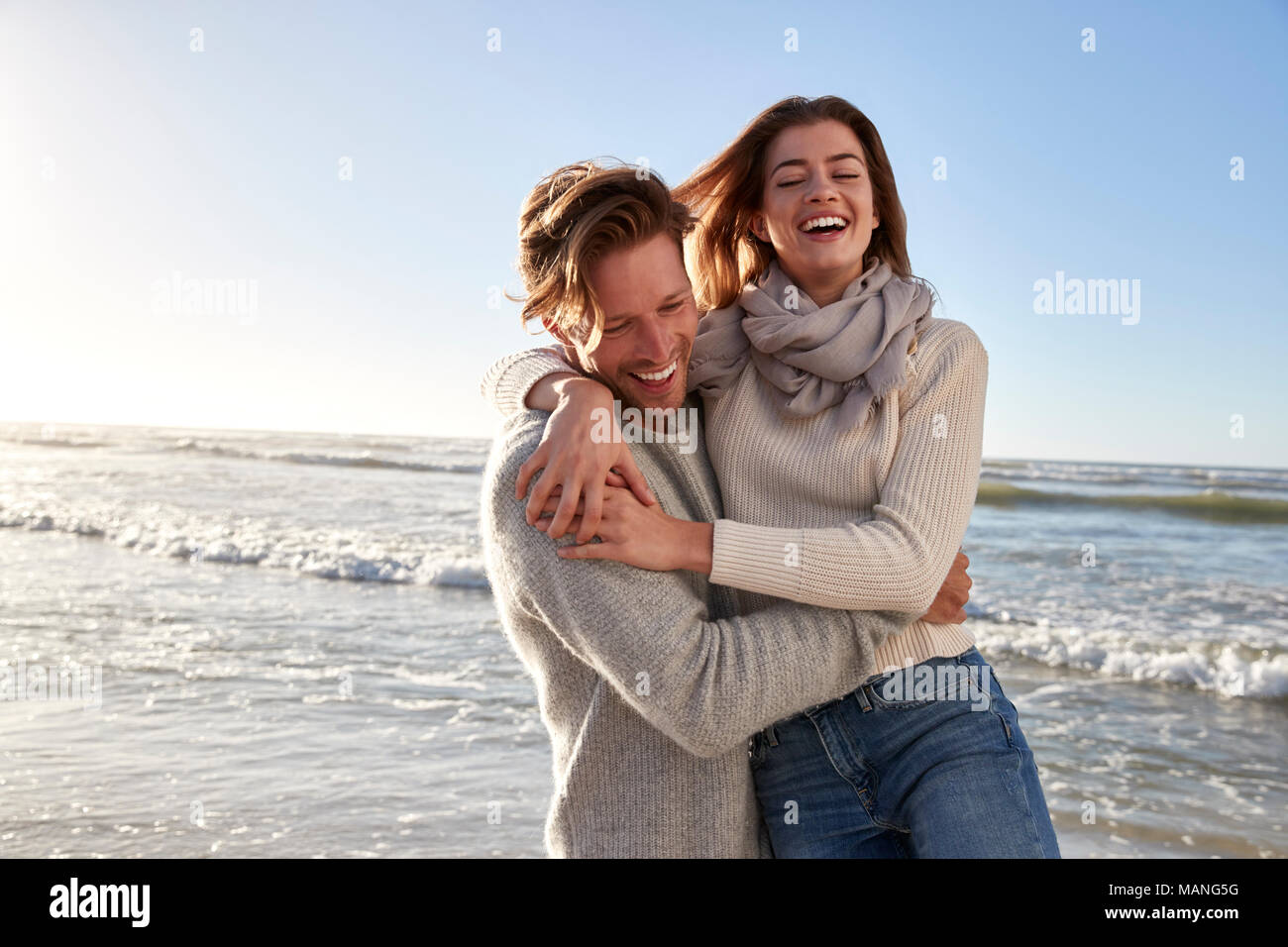 Giovane avendo divertimento sulla spiaggia invernale insieme Foto Stock