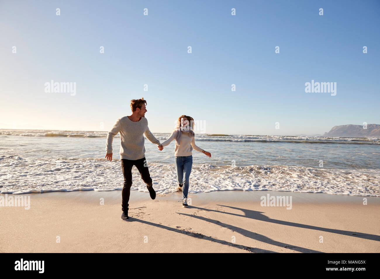 Giovane avendo divertimento lungo la spiaggia invernale insieme Foto Stock