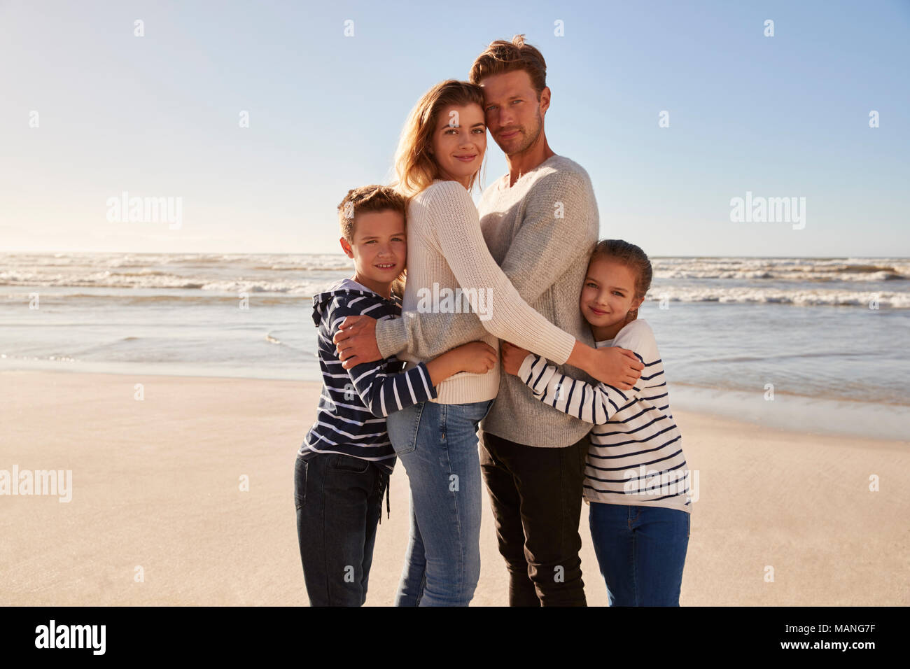 Ritratto di famiglia amorevole abbracciando sulla Spiaggia Invernale Foto Stock