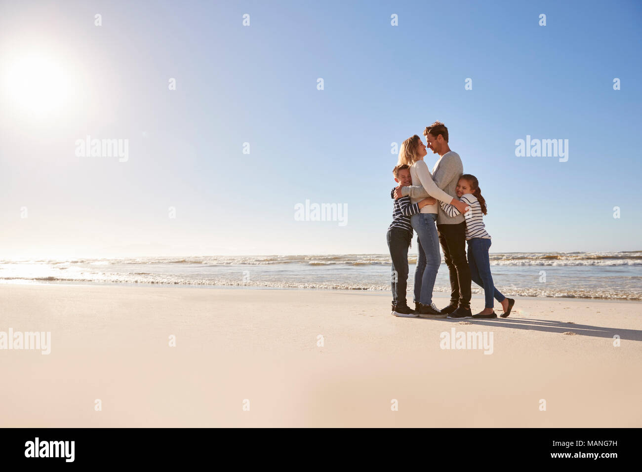 Famiglia amorevole abbracciando sulla Spiaggia Invernale Foto Stock