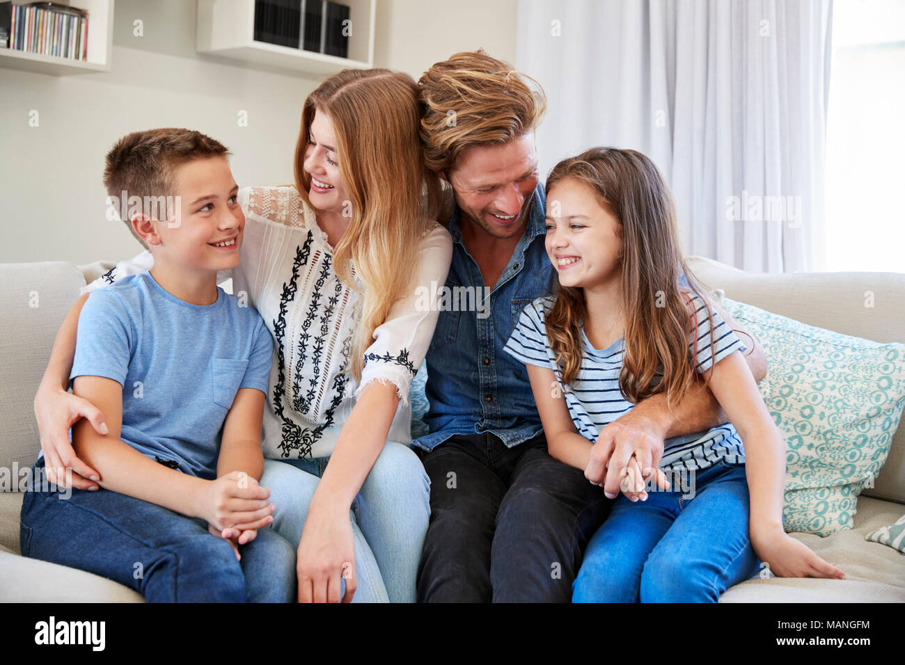 Famiglia sorridente rilassante sul divano di casa insieme Foto Stock