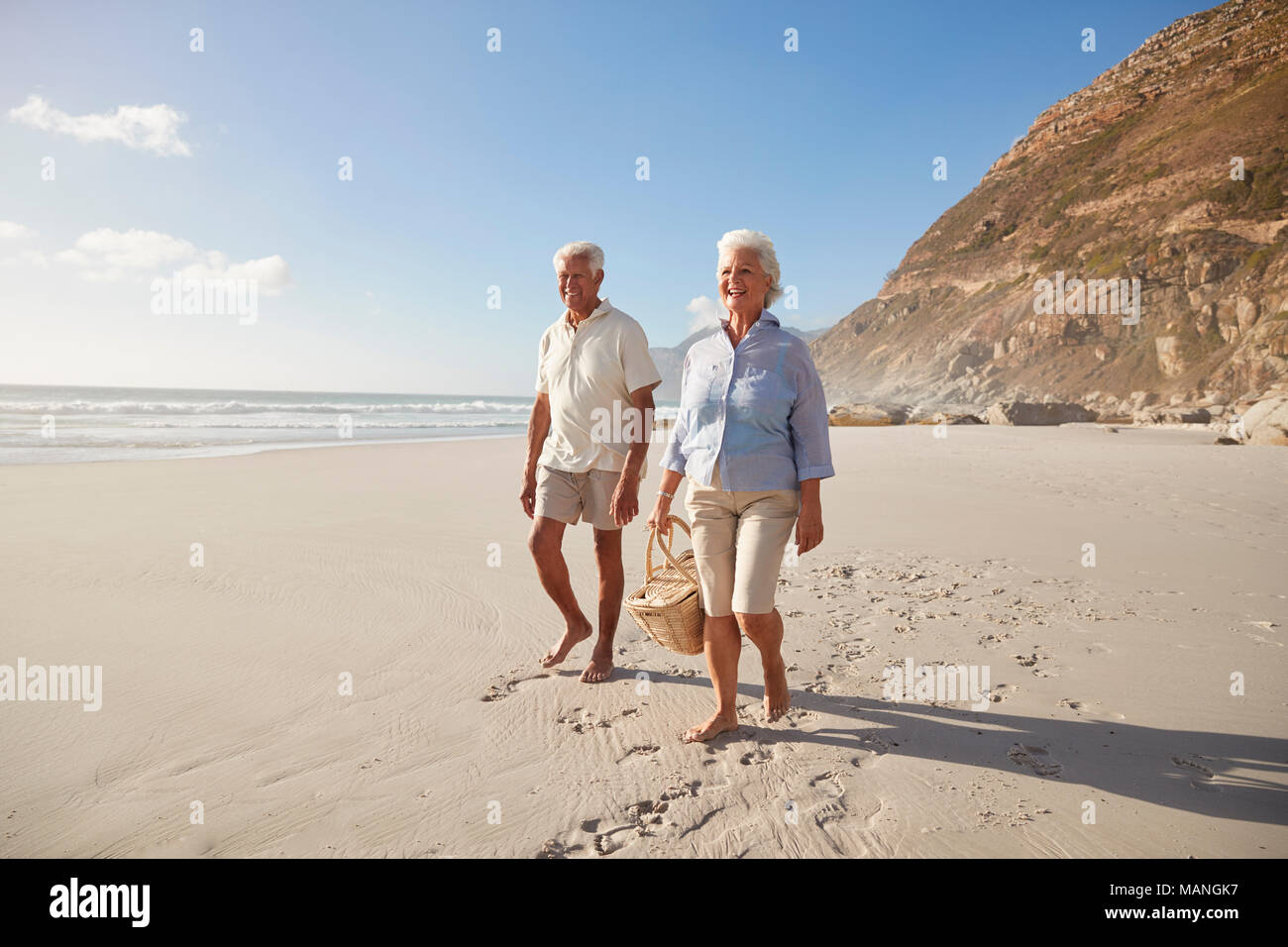 Senior pensionati giovane camminando lungo la spiaggia mano nella mano insieme Foto Stock