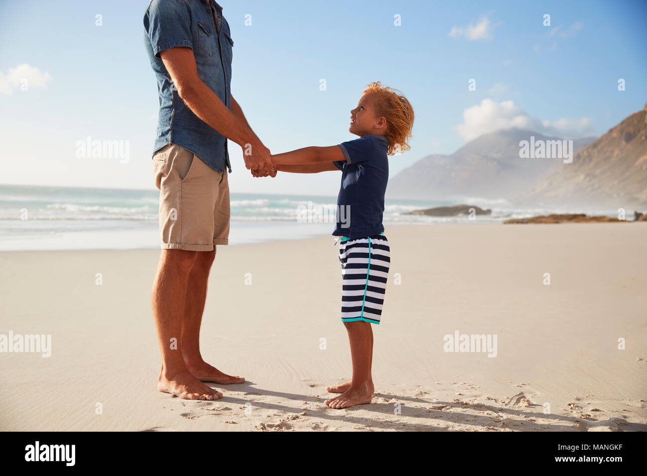Padre tenendo le mani con il figlio in estate vacanza in spiaggia Foto Stock