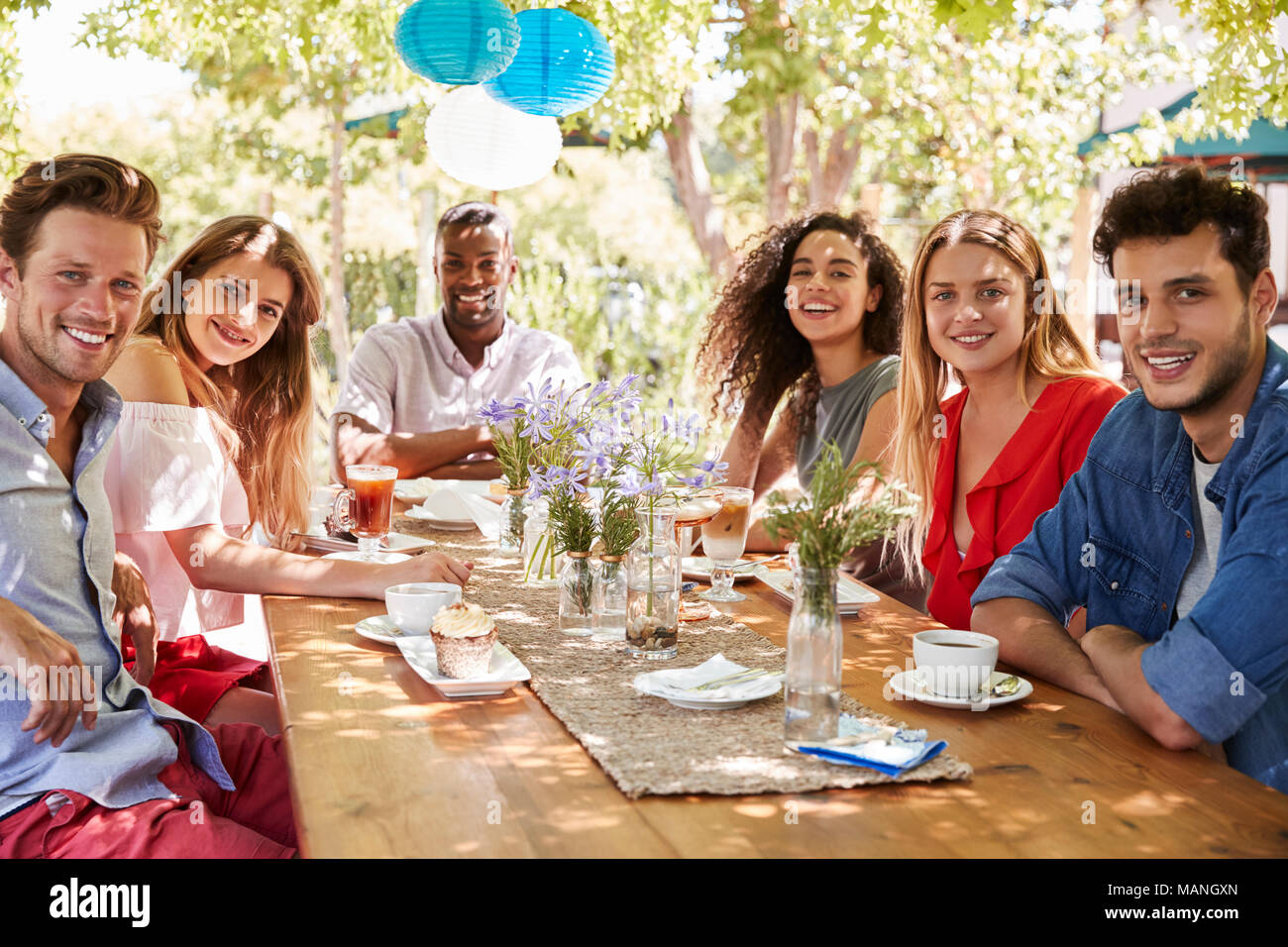 Sei giovani amici adulti cenare all'aperto di sorridere alla telecamera Foto Stock