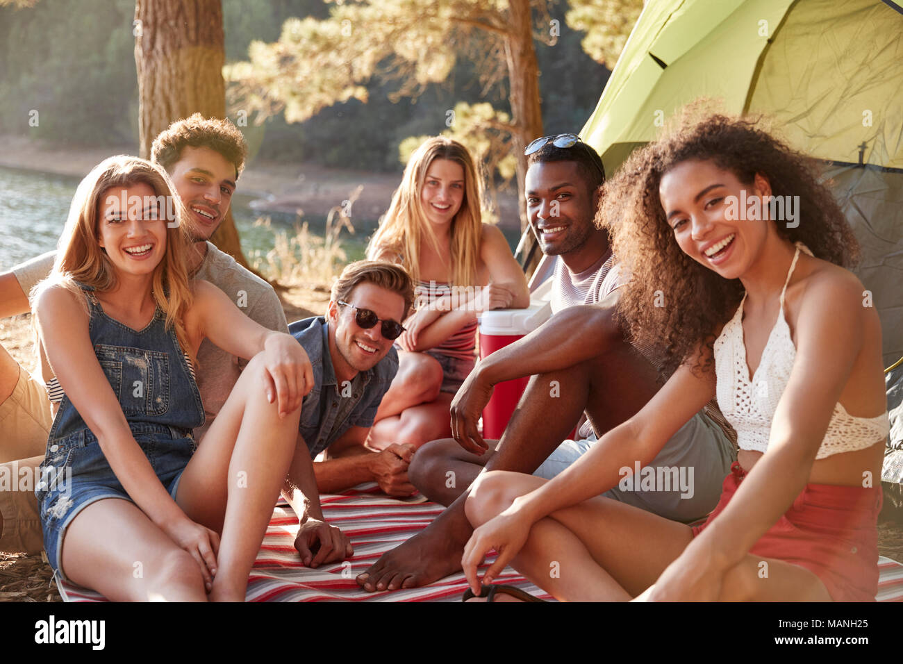 Amici relax su una coperta da un lago, vicino fino Foto Stock