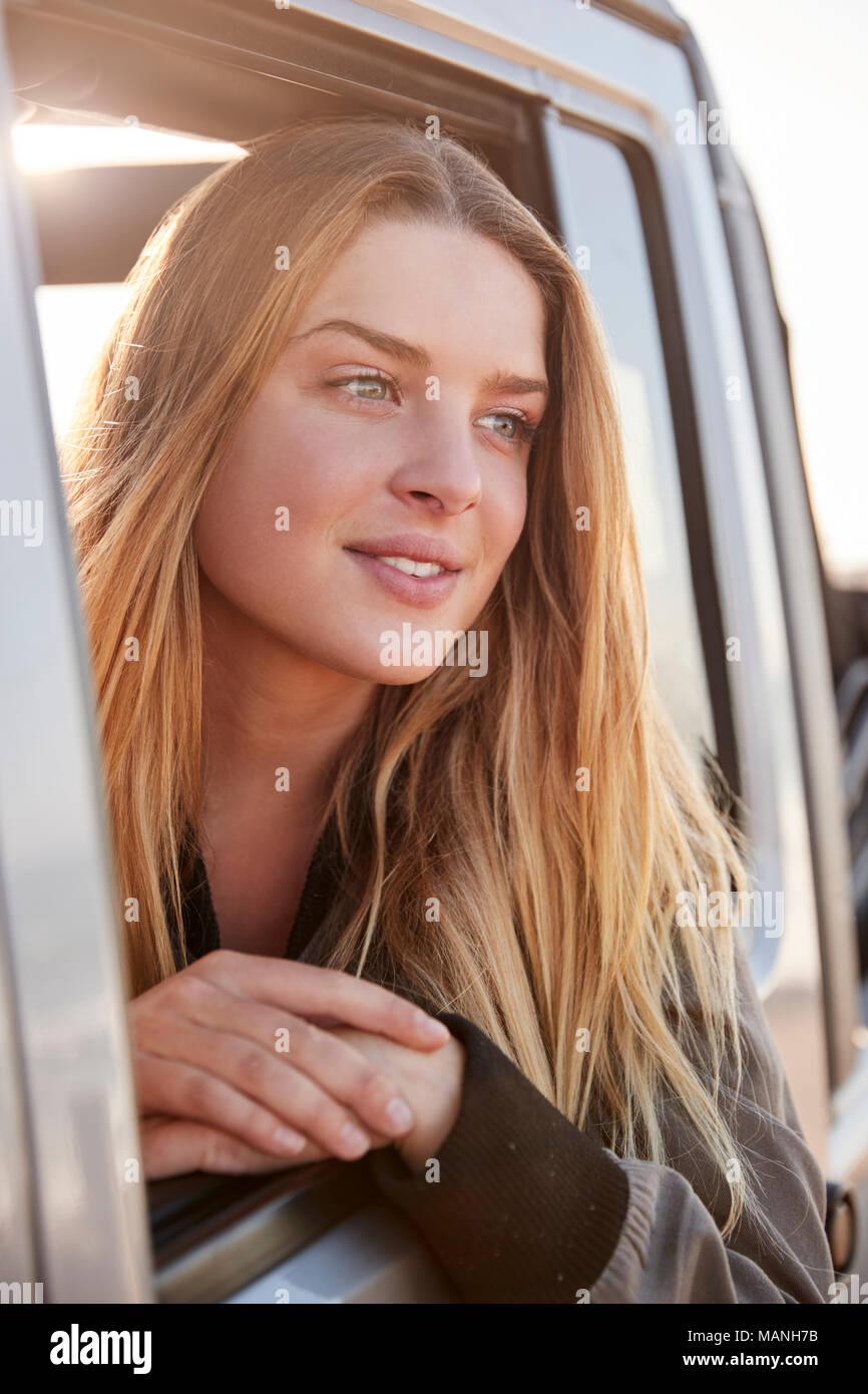 Bianco giovane donna che guarda lontano attraverso la finestra aperta di una macchina Foto Stock