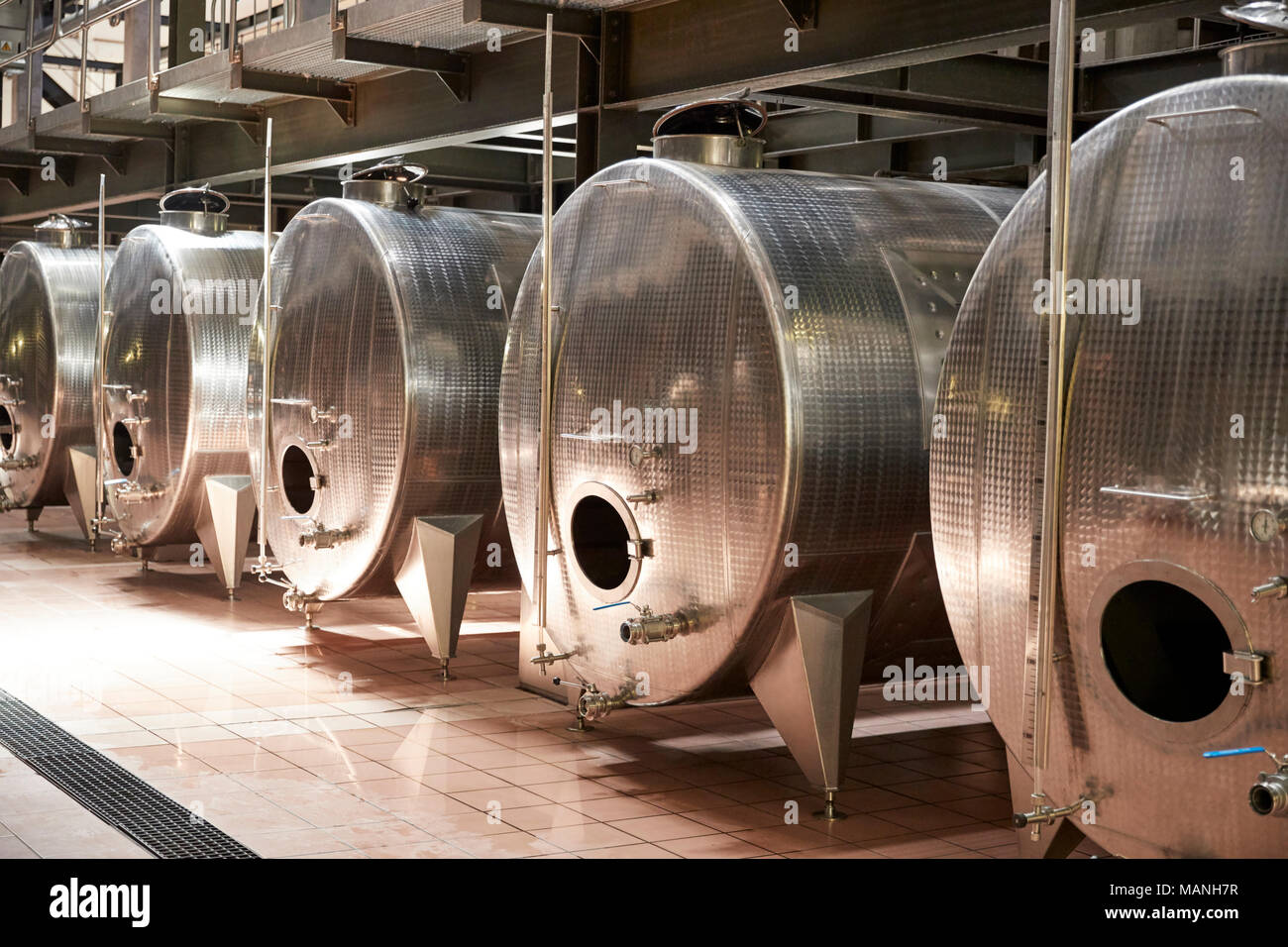 Una fila di recipienti di metallo in un moderno impianto di vinificazione Foto Stock