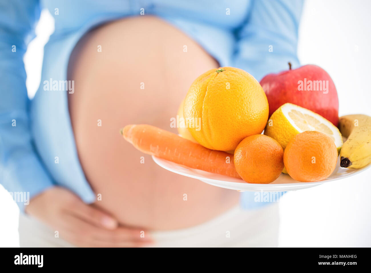 La gravidanza e la nutrizione dieta - donna incinta con frutti studio isolato su sfondo bianco Foto Stock