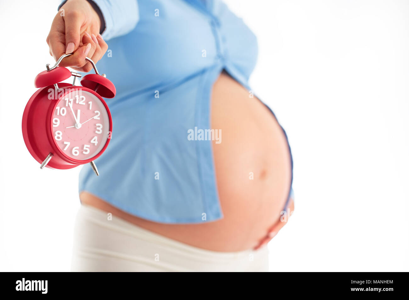 Conta le ore aspettando la nascita del bambino. Concetto di maternità. Donna incinta tenendo sveglia, studio shot. Foto Stock