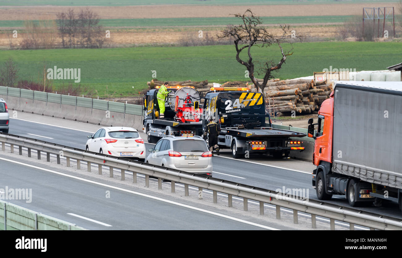 Slovenska Bistrica - Marzo 23, 2018: carroattrezzi lavoratori relitto di pulizia dopo l'incidente di traffico su autostrada dopo un piccolo camion perde il controllo e la sua tr Foto Stock