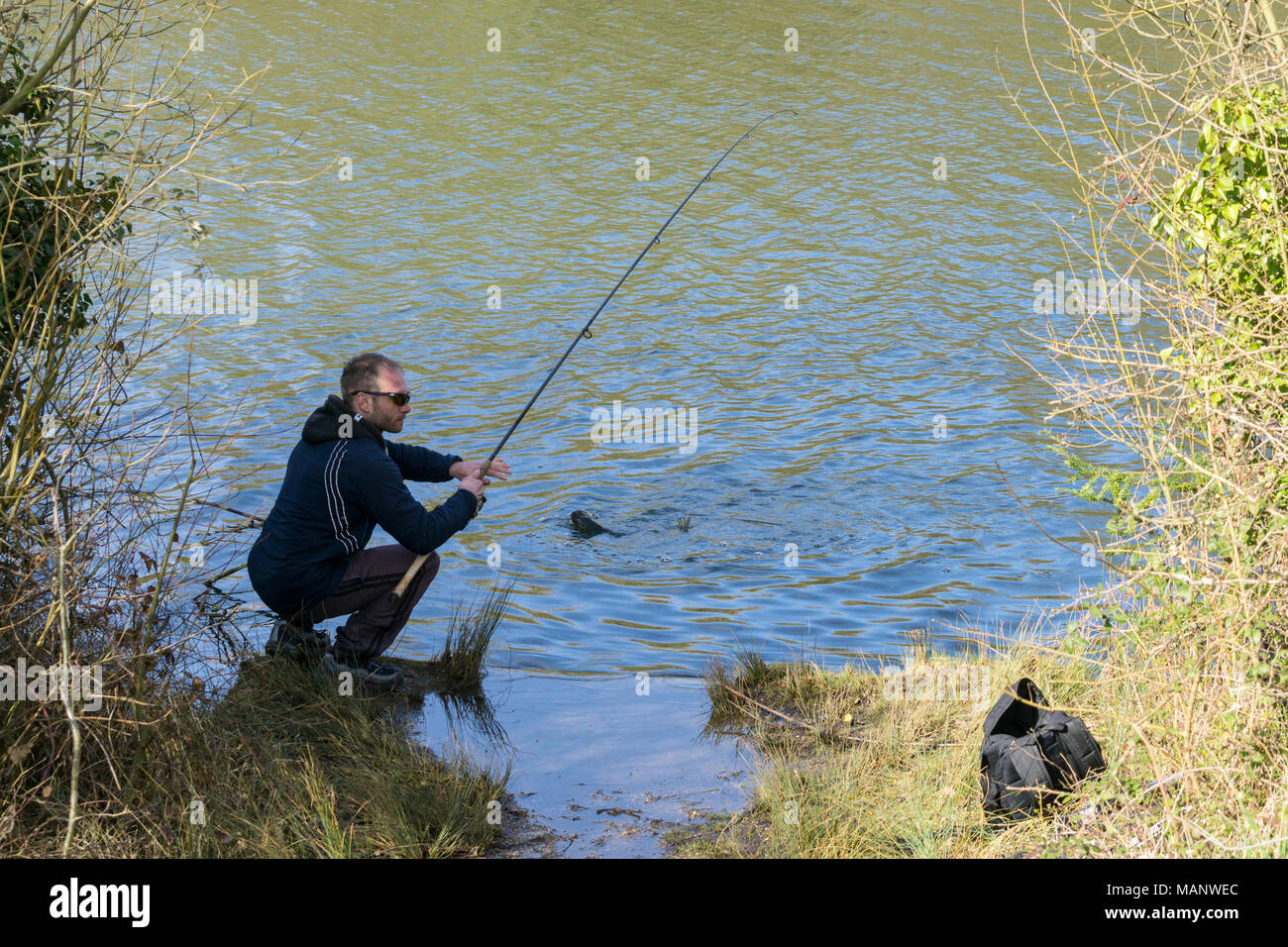 Il pescatore con pesce sul gancio Foto Stock