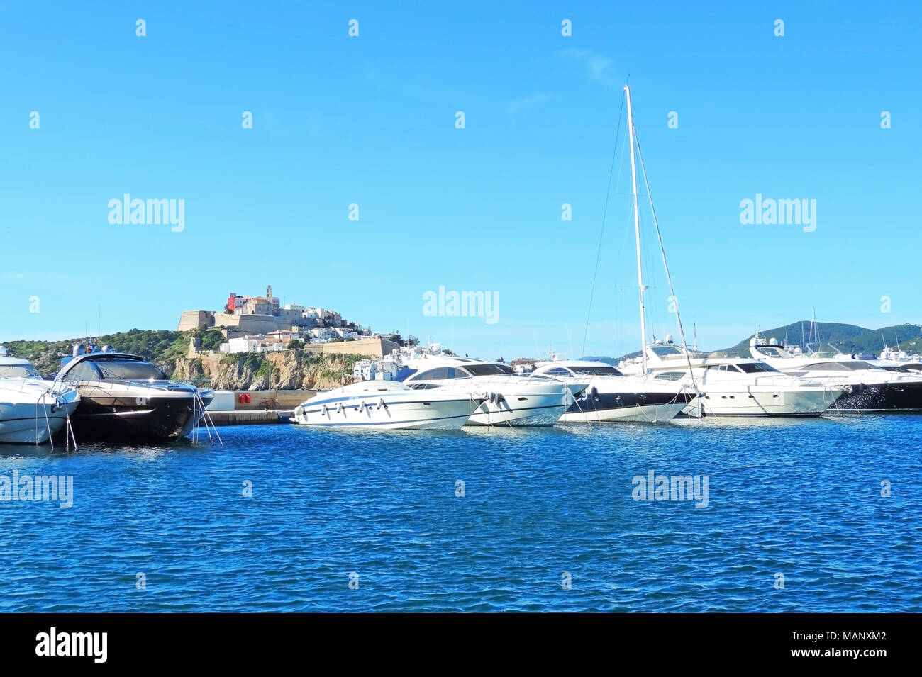 Porto di yacht sulla isola di Ibiza con ancorate barche di lusso e cielo blu chiaro. Barche a vela e barche a motore in un porto. Foto Stock