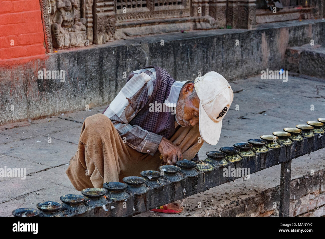 Cera di pulizia da portacandele a un tempio a Kathmandu, Nepal. Foto Stock