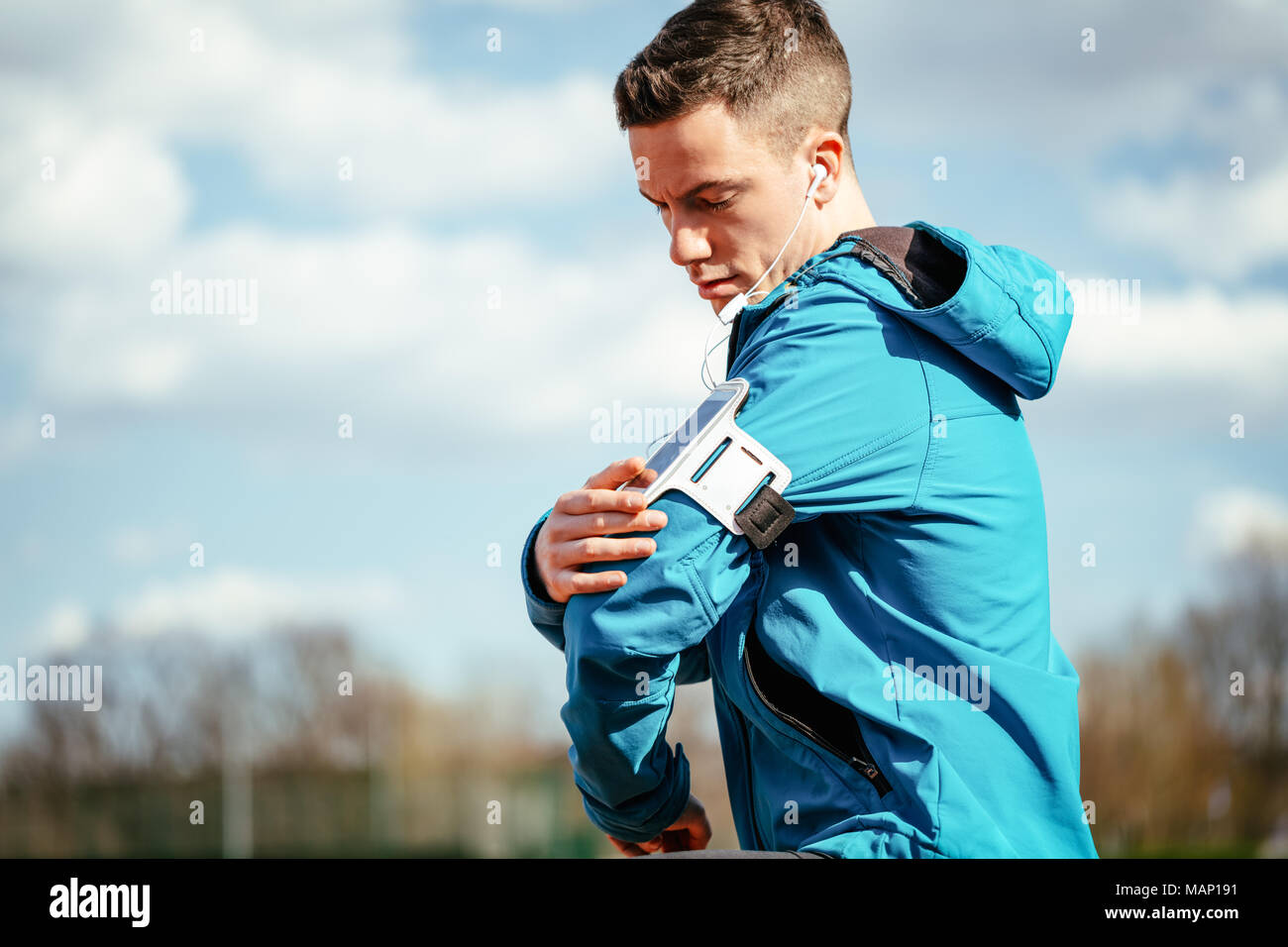 Un maschio di runner con le cuffie sulle orecchie prendendo una pausa in luogo pubblico durante il corso di formazione al di fuori. Copia dello spazio. Foto Stock