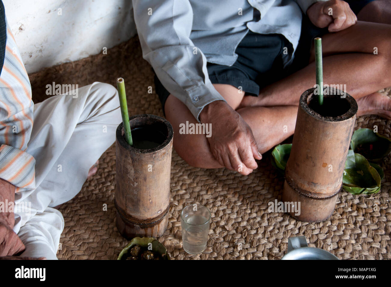 Il Nepal 2014. Pangma village. Nuagi celebrazione. Gli uomini seduti gambe incrociate su un tappeto di bere birra di miglio Foto Stock