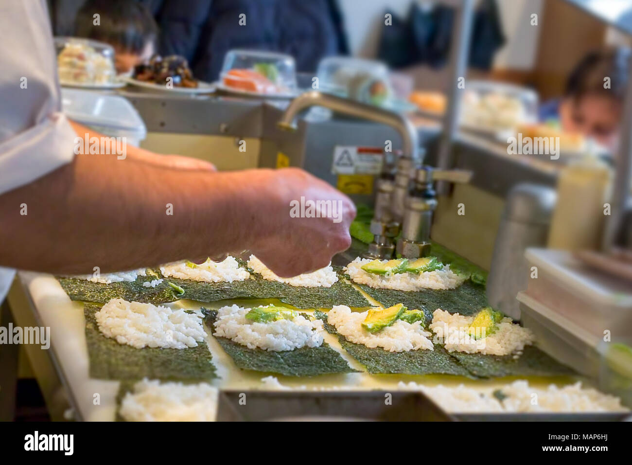 Un sushi chef prepara sushi Uramaki con avocado e salmone fresco Foto Stock
