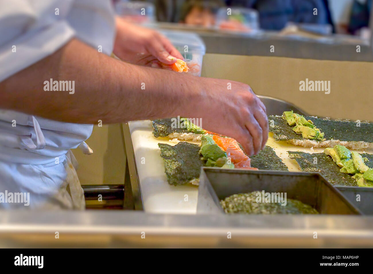 Un sushi chef prepara sushi Uramaki con avocado e salmone fresco Foto Stock