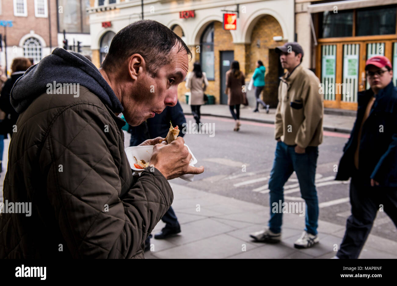 Uomo a mangiare cibo da asporto container vicino mercato di Borough, Southwark, Londra, Inghilterra, Regno Unito Foto Stock