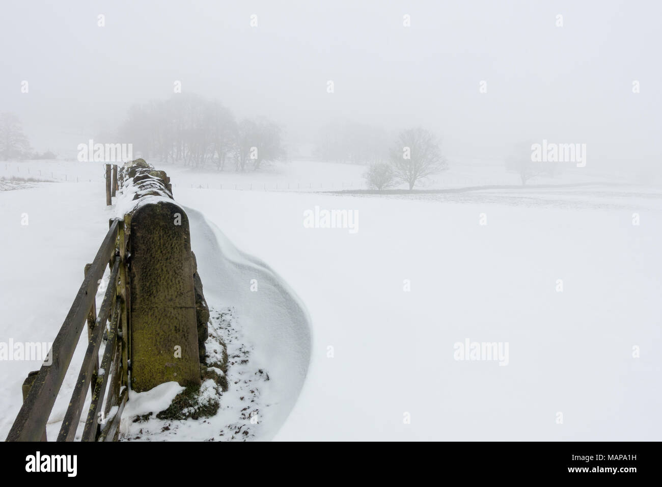 Semplice di immagini di una scena nevoso di campi in campagna con cumuli di neve e un muro di pietra Foto Stock