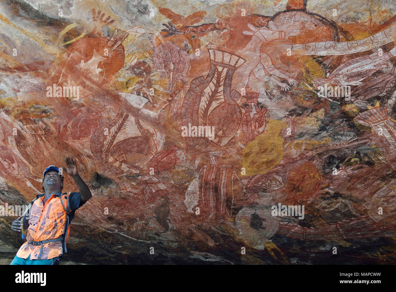 La guida aborigena (Roland) della comunità locale di Gunbalanya mostra l'estesa arte rupestre sulla scarpata a Injalak Hill, Arnhem Land, Australia Foto Stock