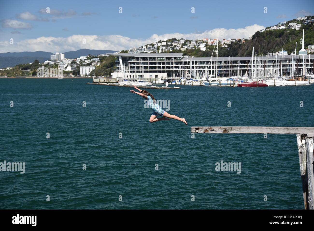 Ragazza saltando in acqua nel porto di Wellington, Nuova Zelanda Foto Stock