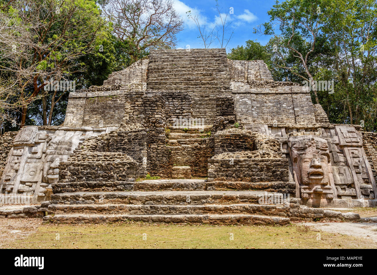 Vecchia pietra antichi Maya di civiltà precolombiane piramide con volto scolpito ed ornamento nascoste nella foresta, Lamanai sito archeologico, Orange Walk Foto Stock