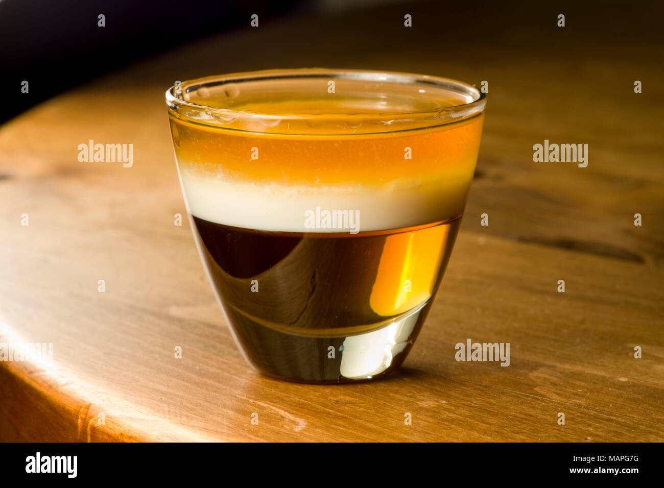 Stratificato bevanda alcolica di sciroppo d'acero, la panna e il rum su uno sfondo di legno. Foto Stock