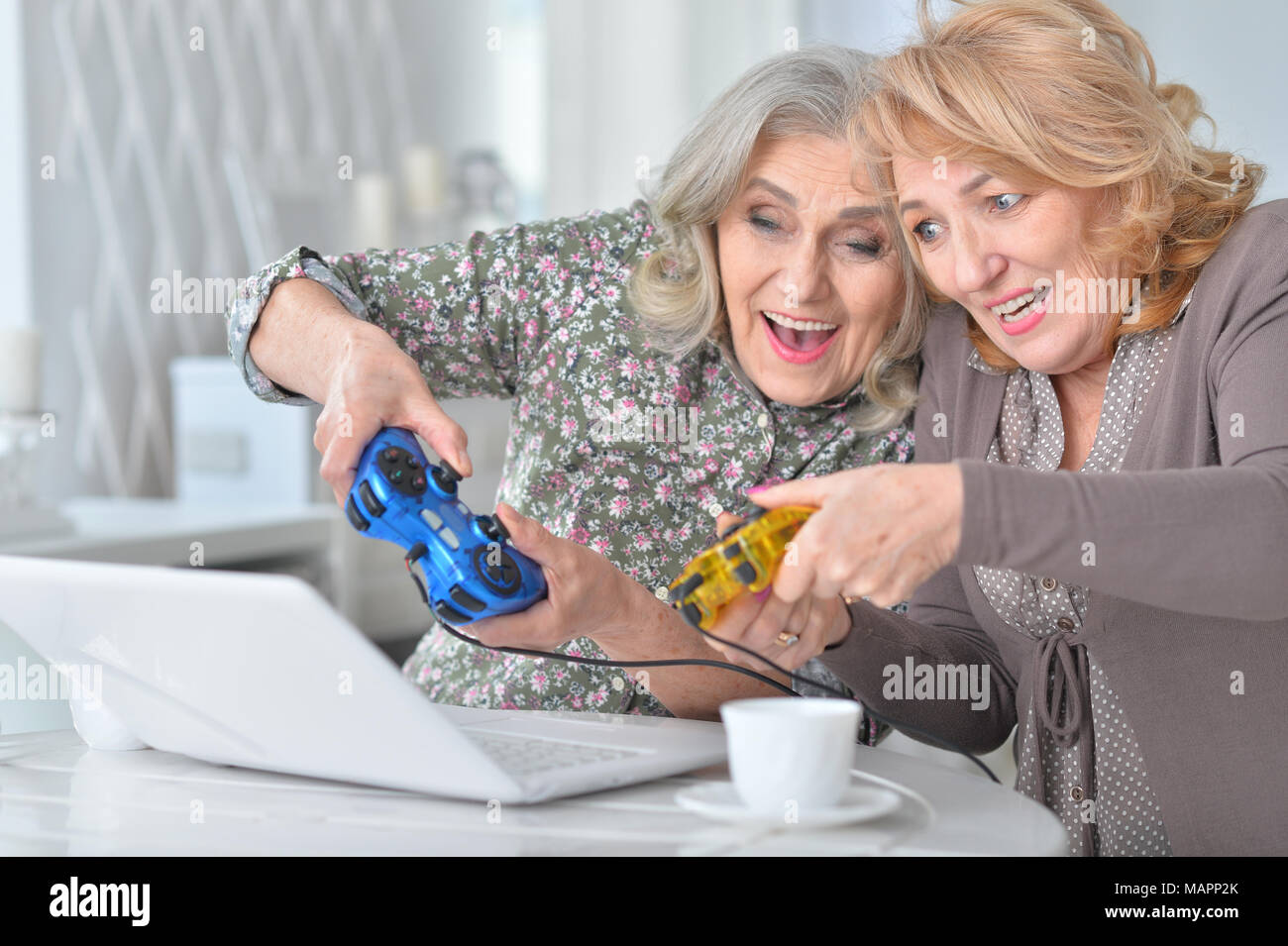 Le donne anziane la riproduzione di gioco per computer con il computer portatile mentre si beve te Foto Stock