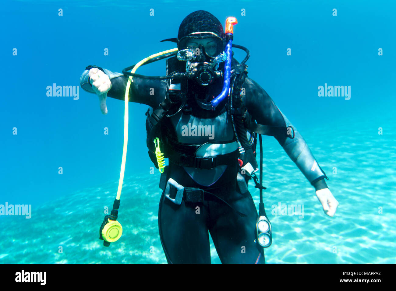 Un ritratto di un subacqueo in mare, che mostra il segno "immersione" (iniziare a muoversi verso il basso) Foto Stock