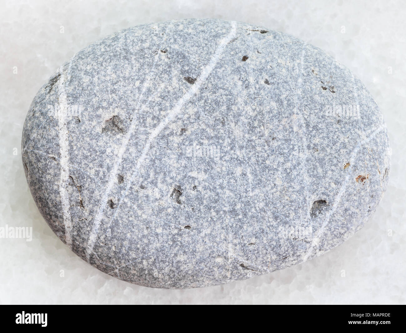 Le riprese in modalità macro di minerale naturale campione di roccia - burattati grauwacke arenaria bianca su sfondo marmo Foto Stock