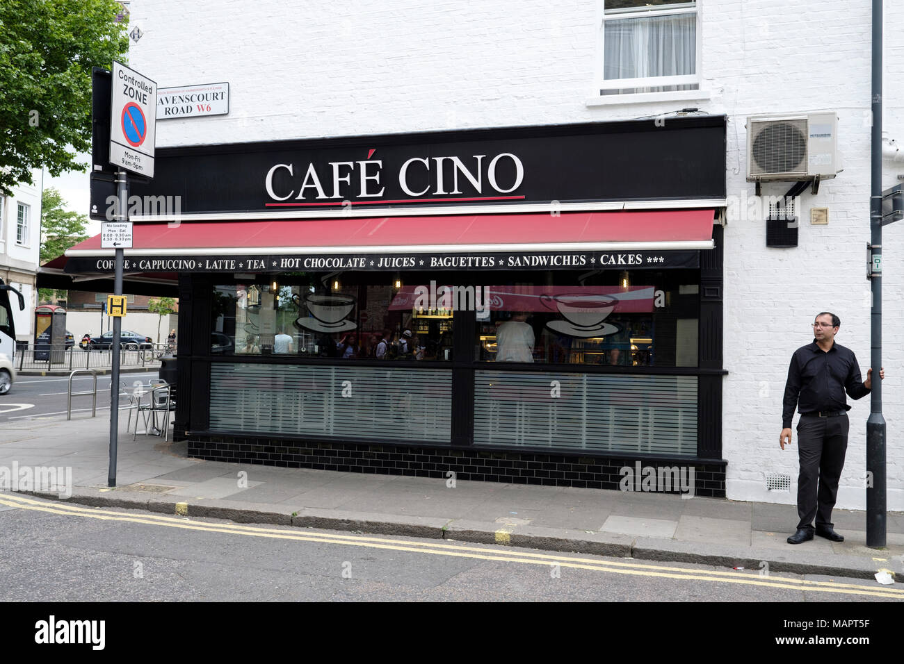 Un uomo in piedi dal Café Cino in Hammersmith, Londra, Regno Unito. Foto Stock