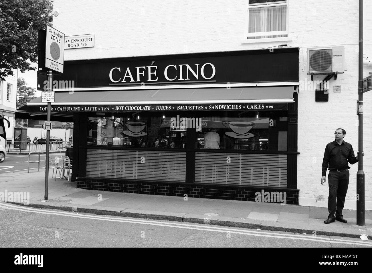 Un uomo in piedi dal Café Cino in Hammersmith, Londra, Regno Unito. Foto Stock