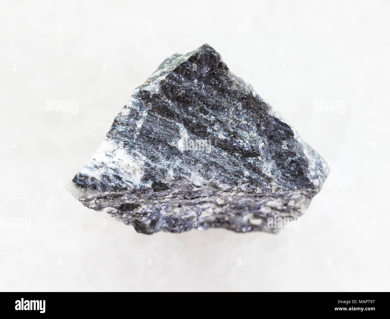 Le riprese in modalità macro di minerale naturale campione di roccia - stibnite ruvida (antimonite) minerale sul marmo bianco sullo sfondo Foto Stock