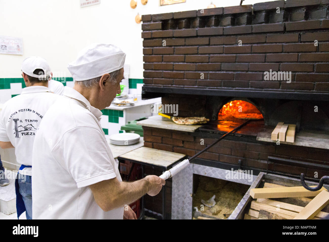 Uomo di cucina italiana tradizionale pizza nel forno a legna presso l'antica pizzeria da Michele, Napoli, Italia Foto Stock
