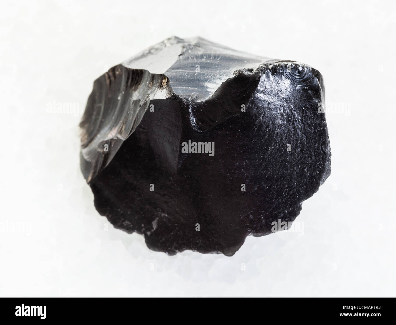 Le riprese in modalità macro di minerale naturale campione di roccia - materie ossidiana (vetro vulcanico) crystal su marmo bianco sullo sfondo Foto Stock