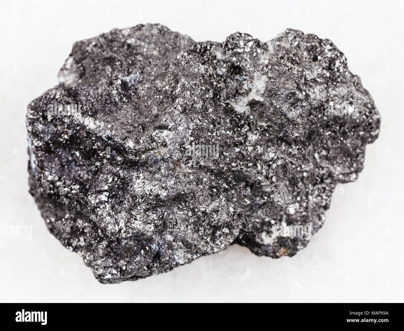 Le riprese in modalità macro di minerale naturale campione di roccia - ruvida pietra di grafite su marmo bianco lo sfondo da Bogotol regione orientale di Sayan montagne, Russ Foto Stock