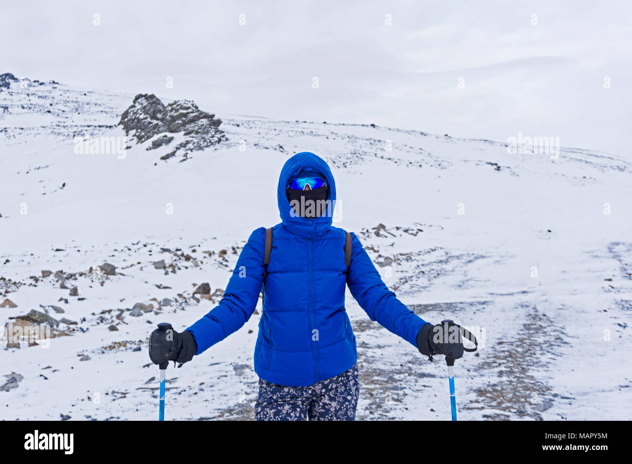 Ragazza traveler o sciatore in vestiti caldi, antivento maschera e occhiali antivento in montagne invernali Foto Stock