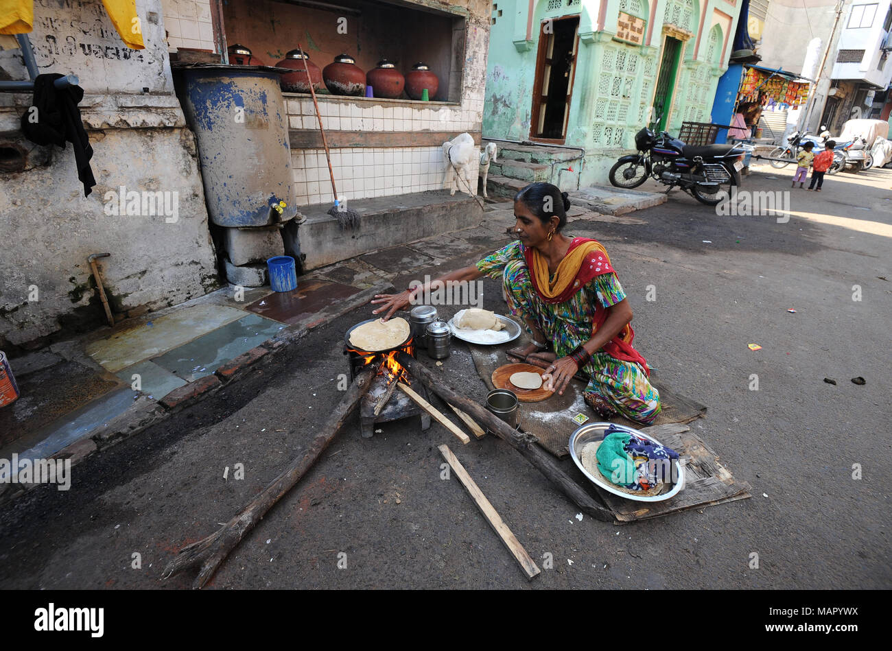 Donna che fa la giornata di chapatis su un fuoco di legno nella strada vicino alla moschea Jama nel vecchio Ahmedabad, Gujarat, India, Asia Foto Stock