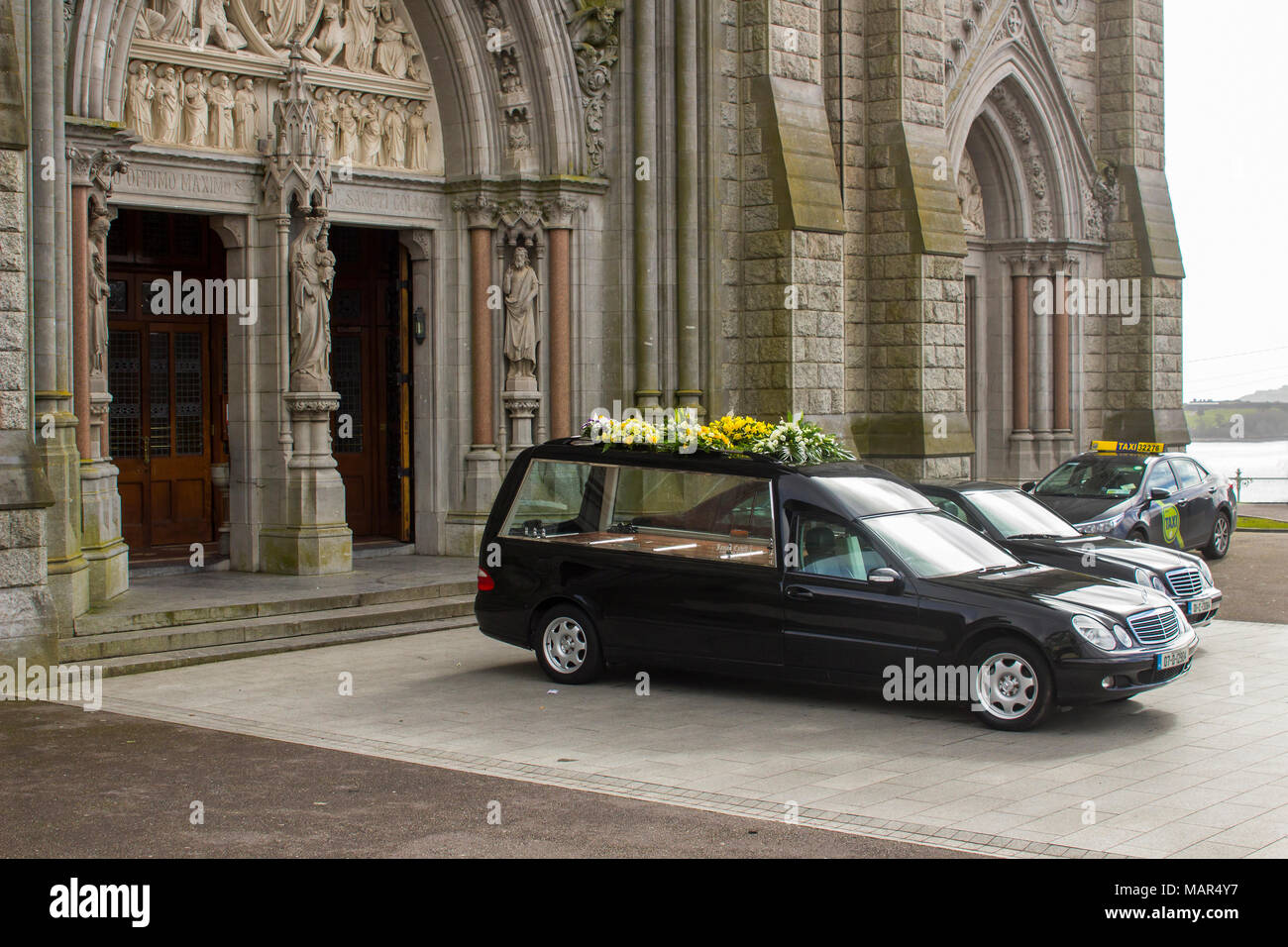 Un'auto funeraria e un'auto parcheggiata fuori da St Colman's. Cattedrale di Cobh Cork Irlanda durante un servizio per un locale dignitario Foto Stock