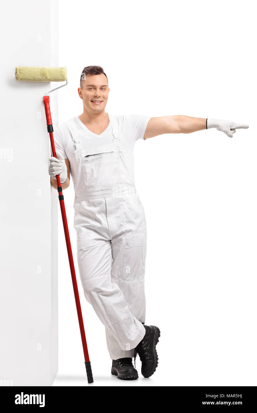 A piena lunghezza Ritratto di un pittore con un rullo di vernice appoggiata contro un muro e puntamento isolati su sfondo bianco Foto Stock