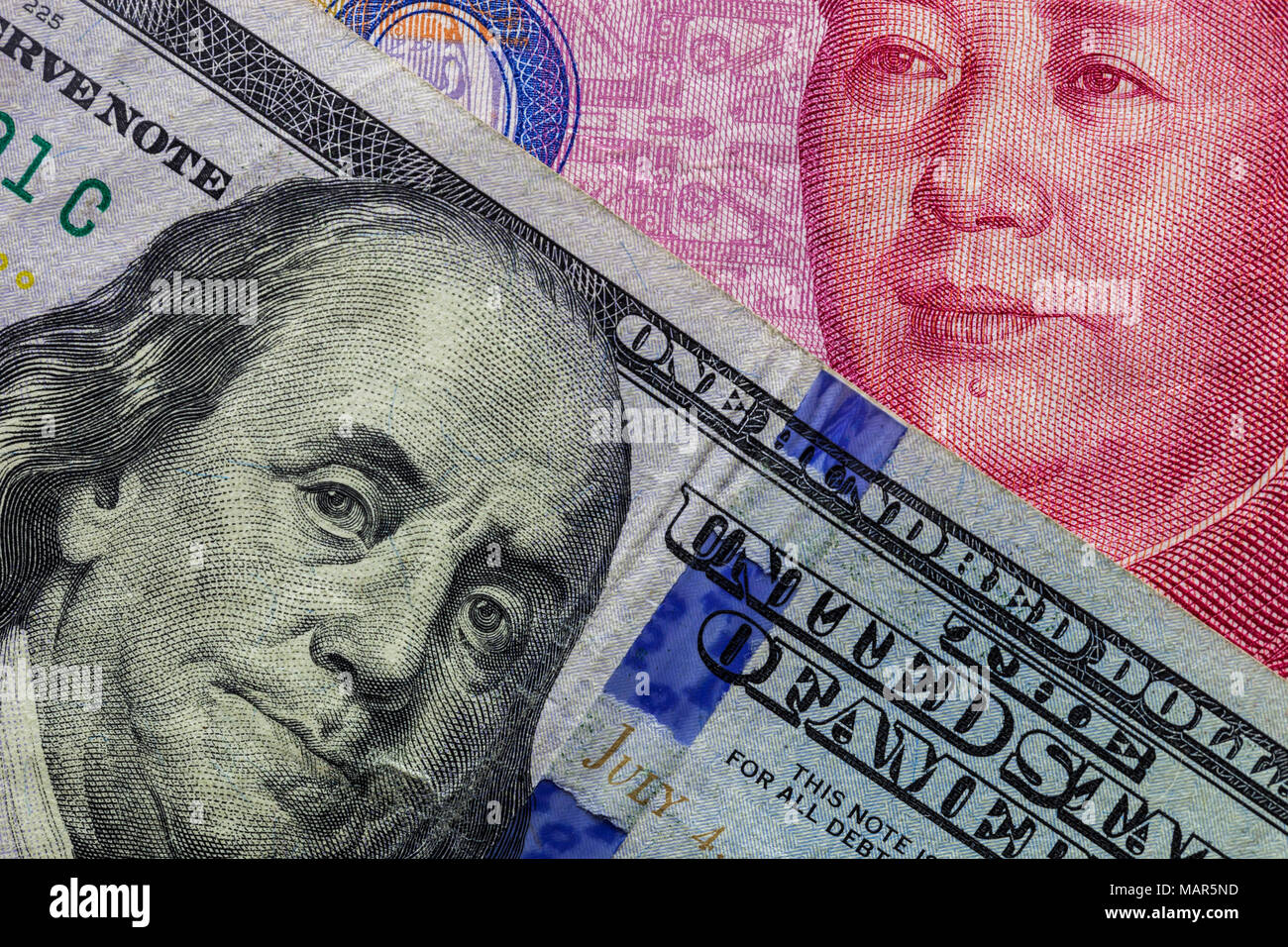 Close up di un centinaio di Dollar banconota oltre a 100 Yuan banconota con focus su ritratti di Benjamin Franklin e di Mao Tse-tung/USA vs Cina guerra commerciale Foto Stock