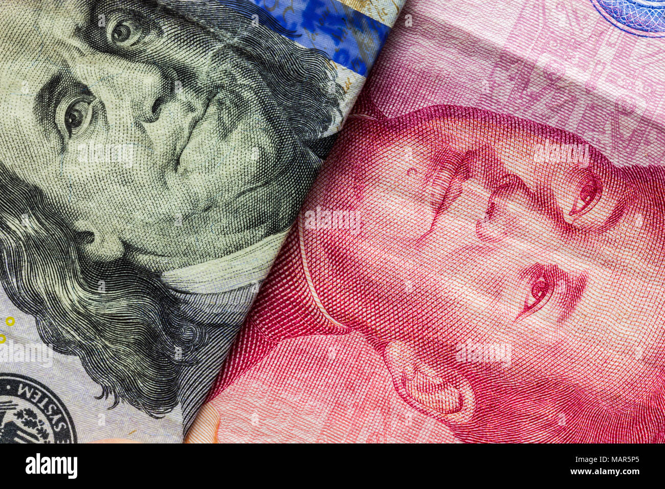 Close up di un centinaio di dollaro e 100 Yaun banconote con focus su ritratti di Benjamin Franklin e di Mao Tse-tung/USA vs Cina guerra commerciale nozione Foto Stock