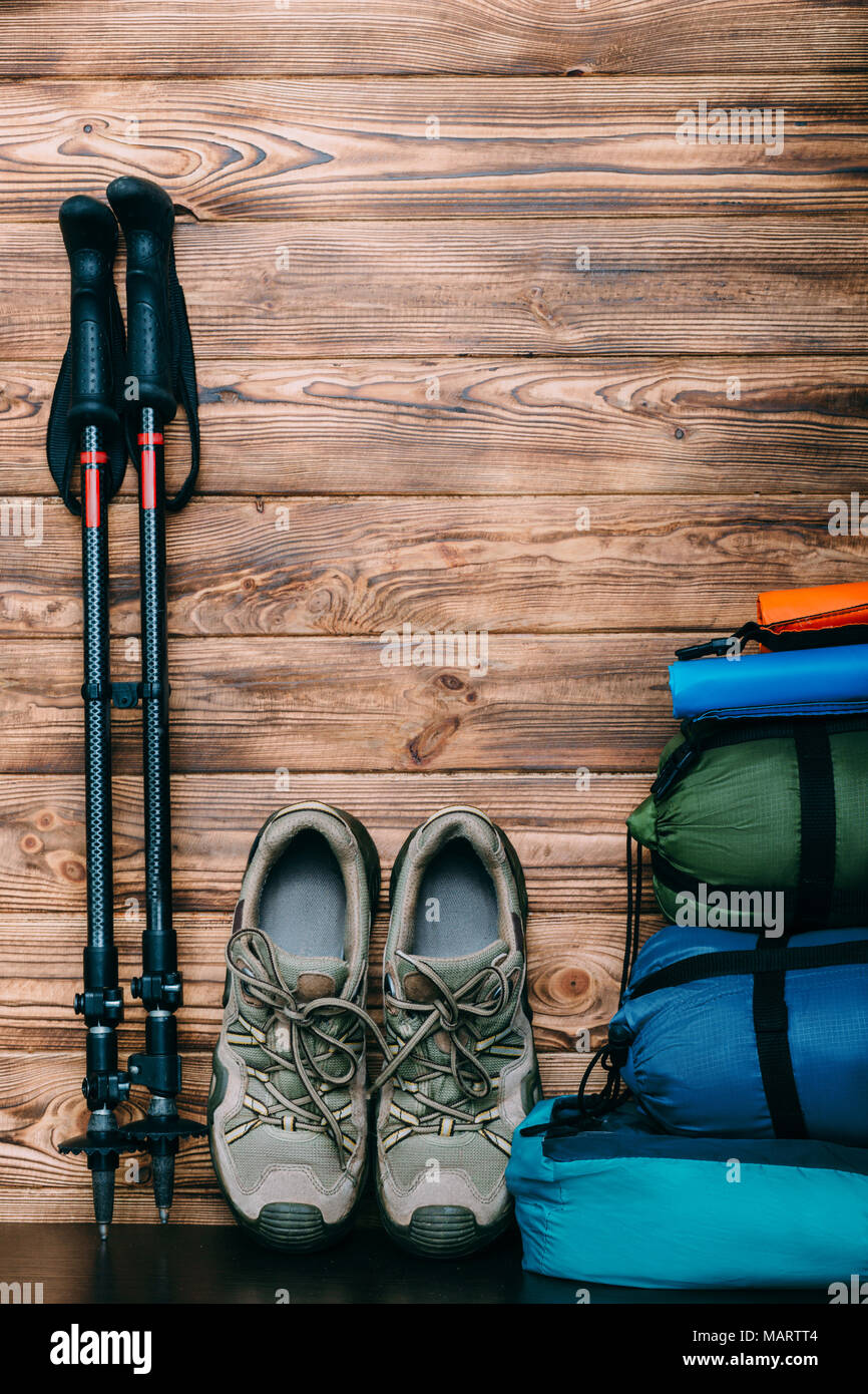 Stile di vita turistica con le scarpe da trekking, sacchi a pelo, tenda e pali trekking su sfondo di legno con copia spazio per il testo Foto Stock
