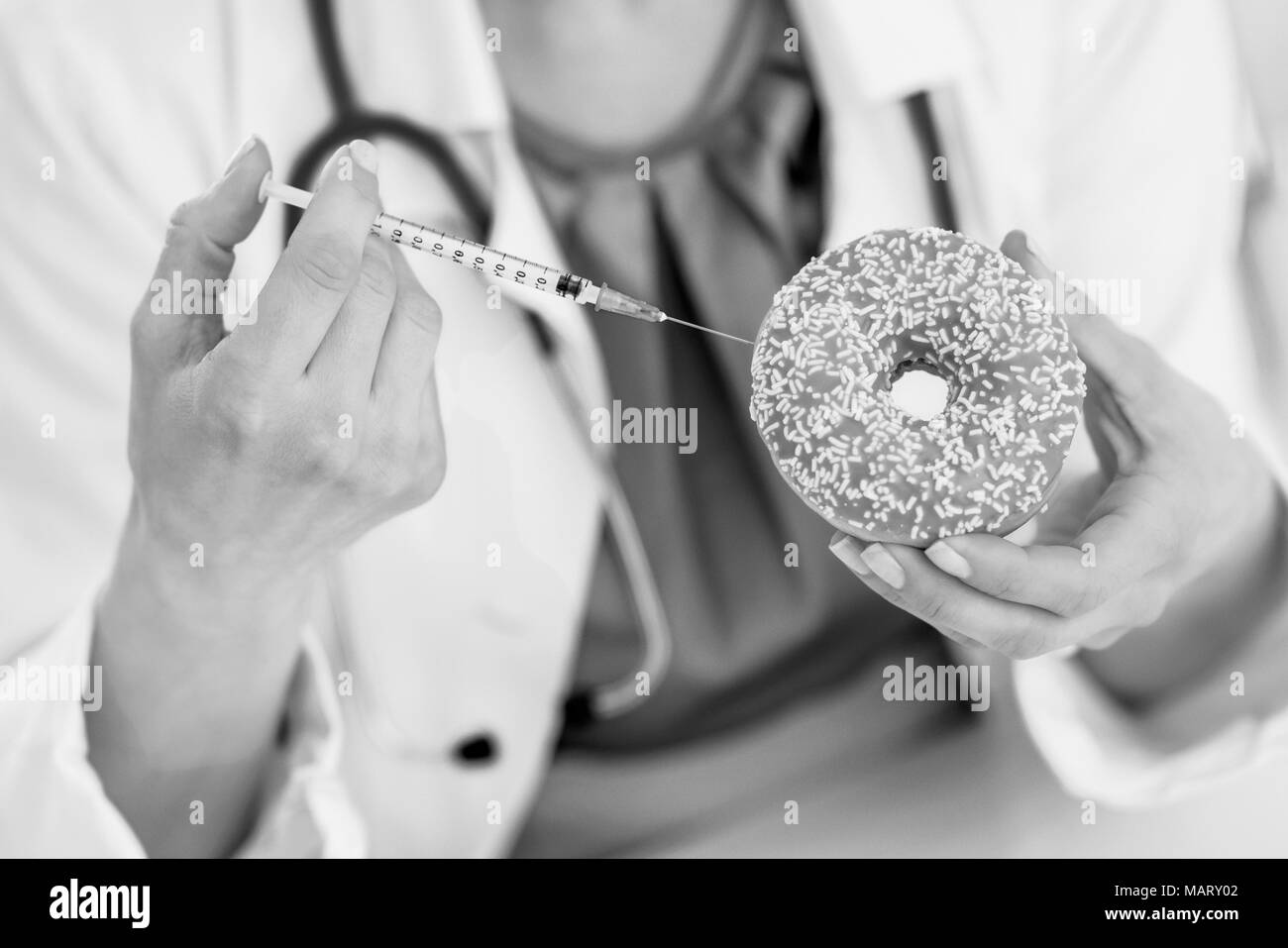 Primo piano sul medico donna fare l'iniezione utilizzando il diabete siringa nella ciambella Foto Stock