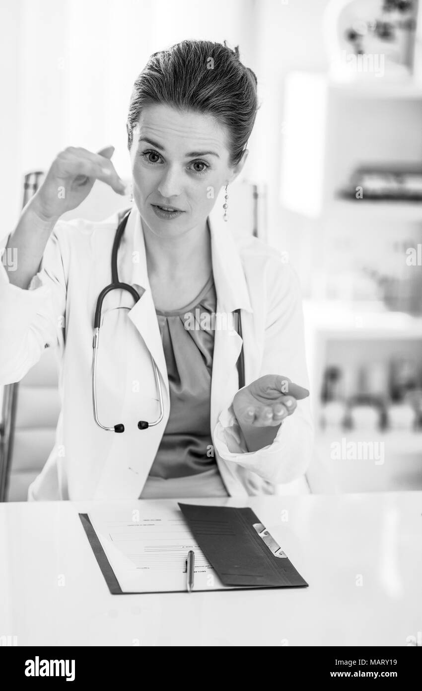 Medico donna seduta in ufficio e spiegare Foto Stock
