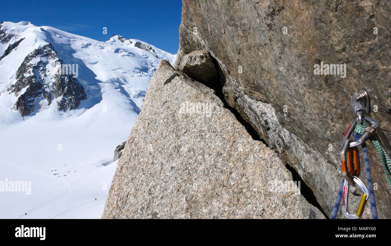 Bullone e quick draw con arrampicata attrezzature su un esposto e ripido percorso di arrampicata nelle Alpi Francesi con Mont Blanc in background Foto Stock