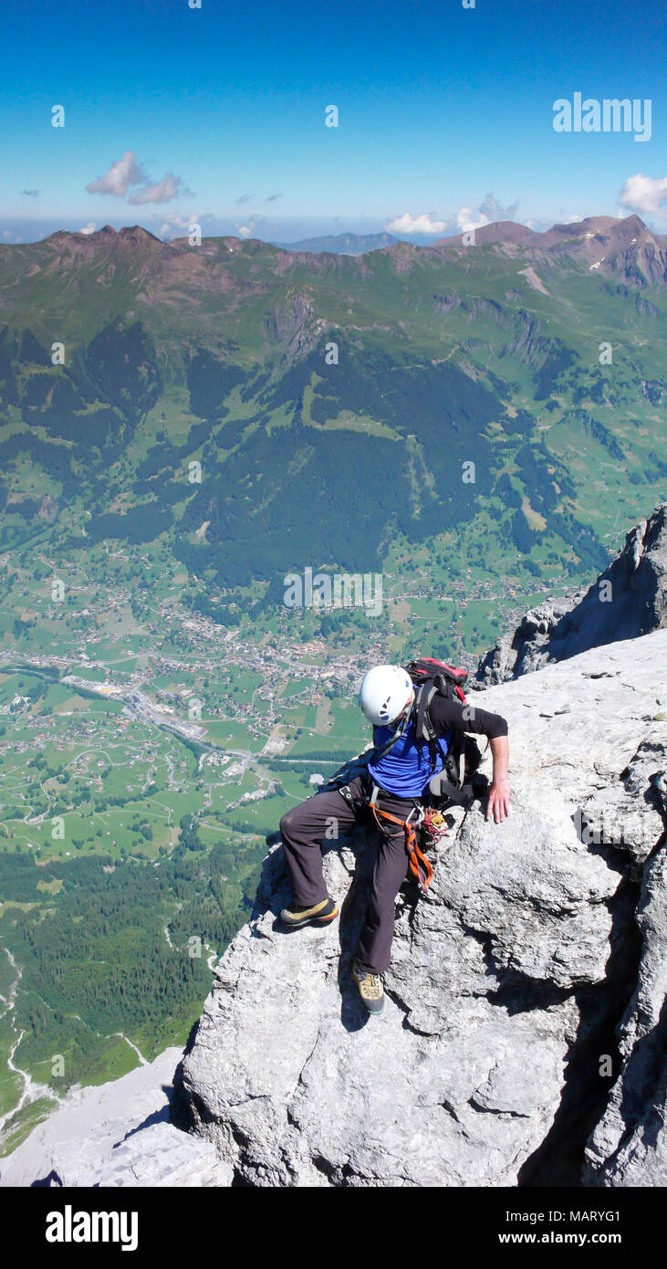 Maschio scalatore di montagna su una stretta ed esposta rock ridge sul suo modo di Eiger montagna nelle Alpi svizzere nei pressi di Grindelwald Foto Stock